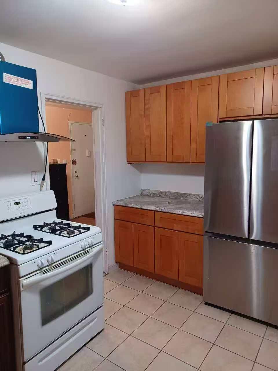 9431 60th Avenue, Unit 1G Queens, NY 11373 - Photo 3 of 7 Kitchen featuring white gas range, exhaust hood, stainless steel fridge, and light tile patterned floors