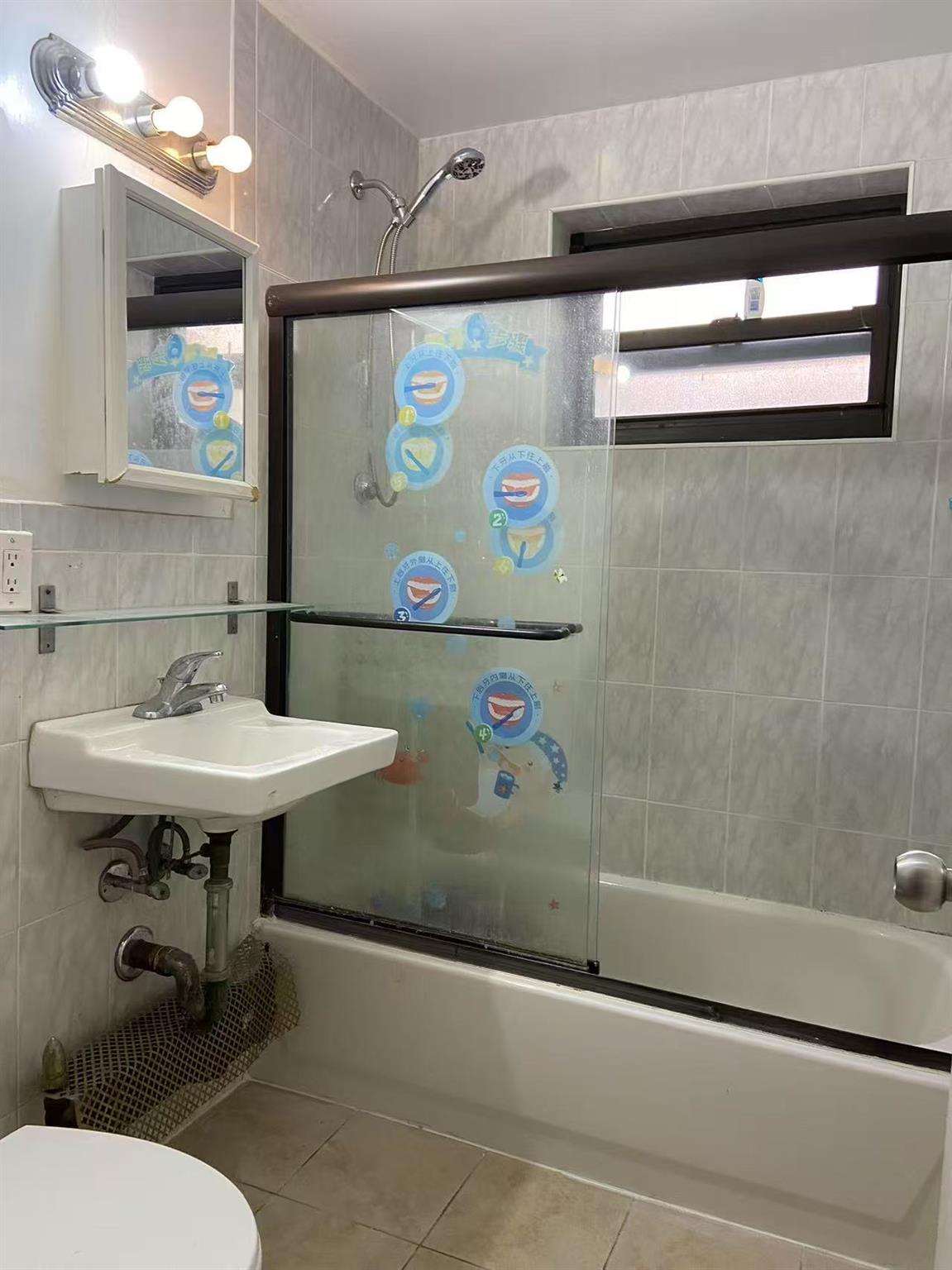 9431 60th Avenue, Unit 1G Queens, NY 11373 - Photo 6 of 7 Bathroom featuring tile walls, bath / shower combo with glass door, toilet, and tile patterned floors