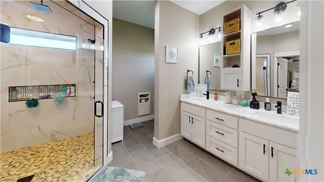 a spacious bathroom with a double vanity sink a toilet a mirror and shower