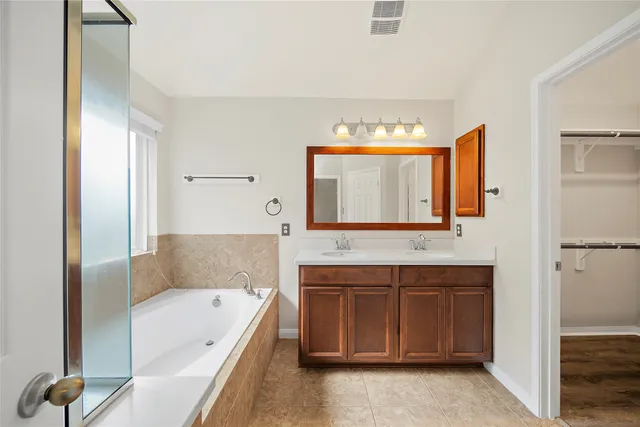 a bathroom with a tub sink and mirror