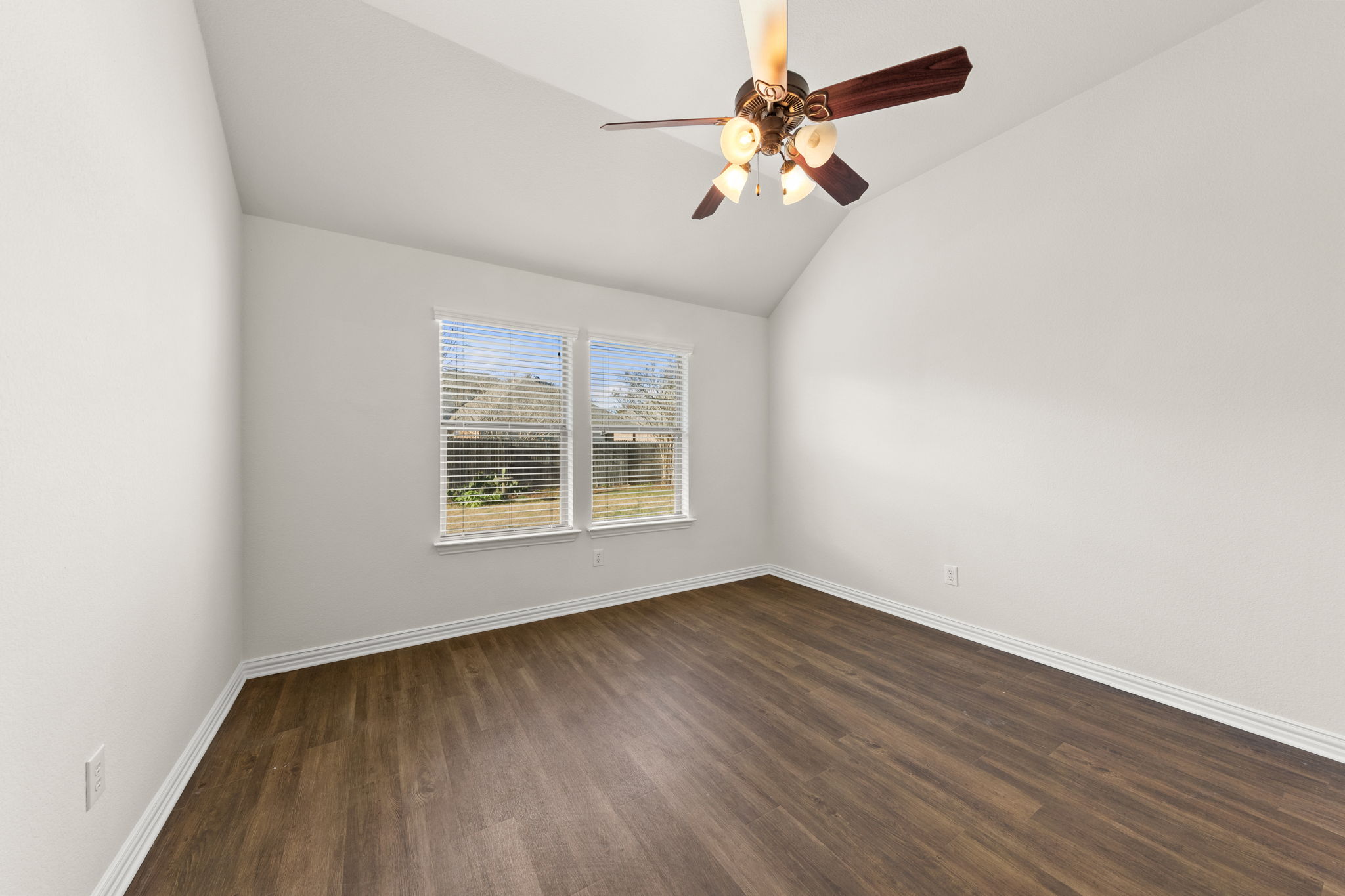 411 Tascate Street Georgetown, TX 78628 - Photo 6 of 41 A spacious room offers vaulted ceilings and rich wood flooring, complemented by generous natural light from two large windows.