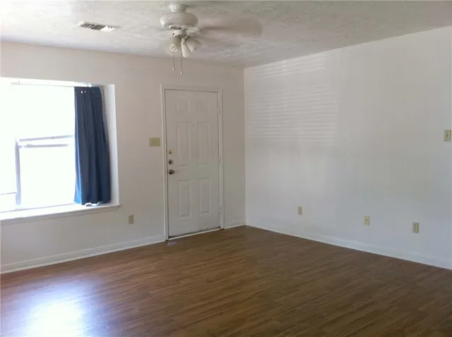 an empty room with wooden floor and windows