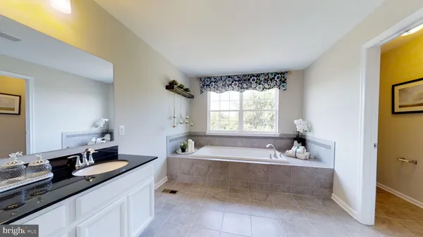 a spacious bathroom with a tub sink and mirror