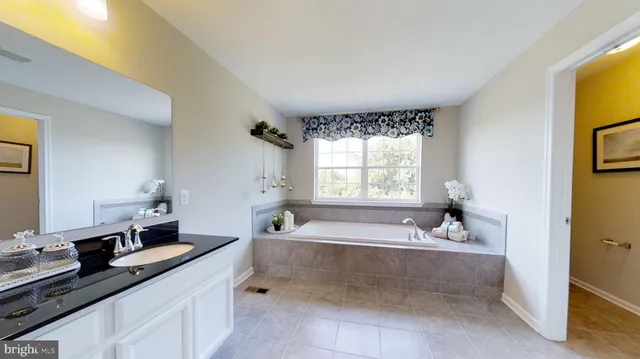 a spacious bathroom with a tub sink and mirror