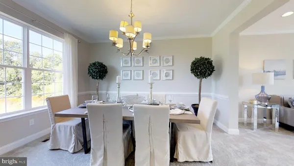 a view of a dining room with furniture a chandelier and large windows