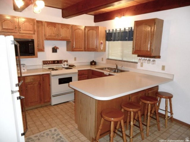 1456 Navajo Road Coalville, UT 84017 - Photo 14 of 55 Kitchen with a breakfast bar area, a peninsula, white appliances, light countertops, and light flooring