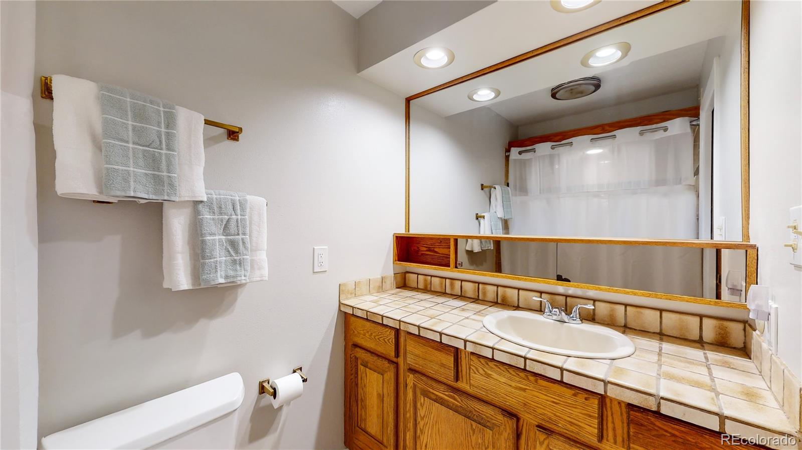 8020 Cyprus Road Colorado Springs, CO 80908 - Photo 19 of 42 a bathroom with a granite countertop sink a mirror and a shower