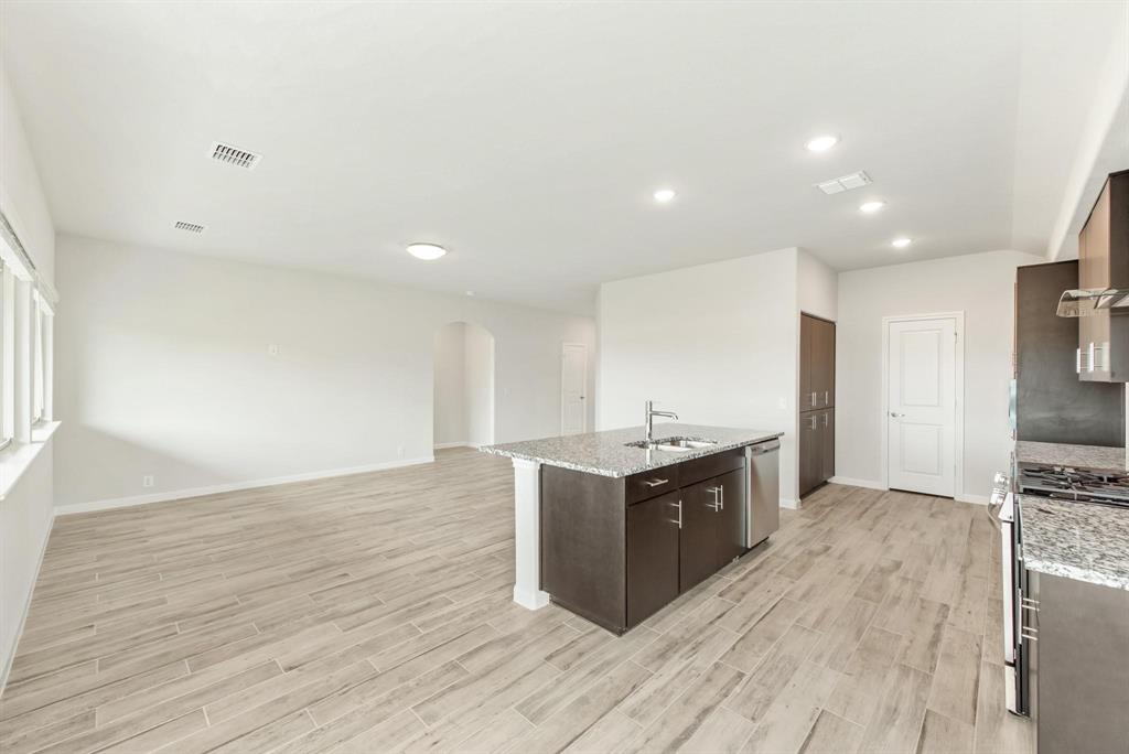 920 Elk Ridge Run Godley, TX 76044 - Photo 12 of 34 Open-concept living area featuring wood-finish flooring, recessed lighting, and a kitchen island with granite countertops