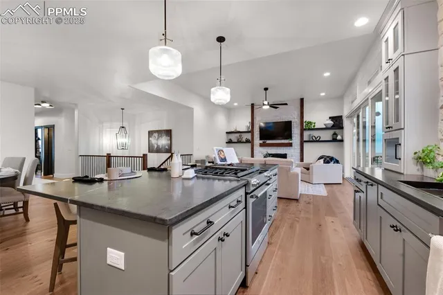a living room with furniture a view of kitchen and a chandelier fan