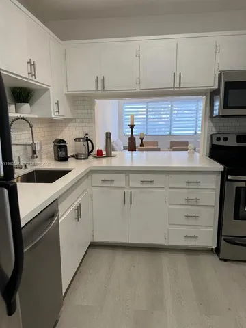 a kitchen with cabinets appliances a sink and a counter top
