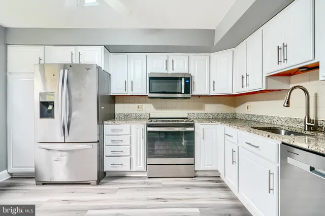 a kitchen with granite countertop white cabinets and stainless steel appliances