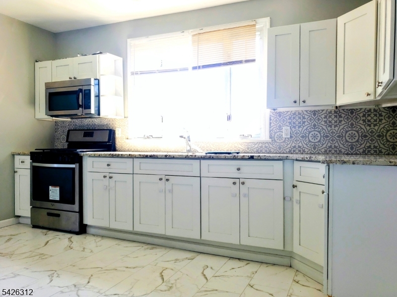 215 Lafayette Street Orange, NJ 07050 - Photo 11 of 14 a kitchen with granite countertop white cabinets and stainless steel appliances