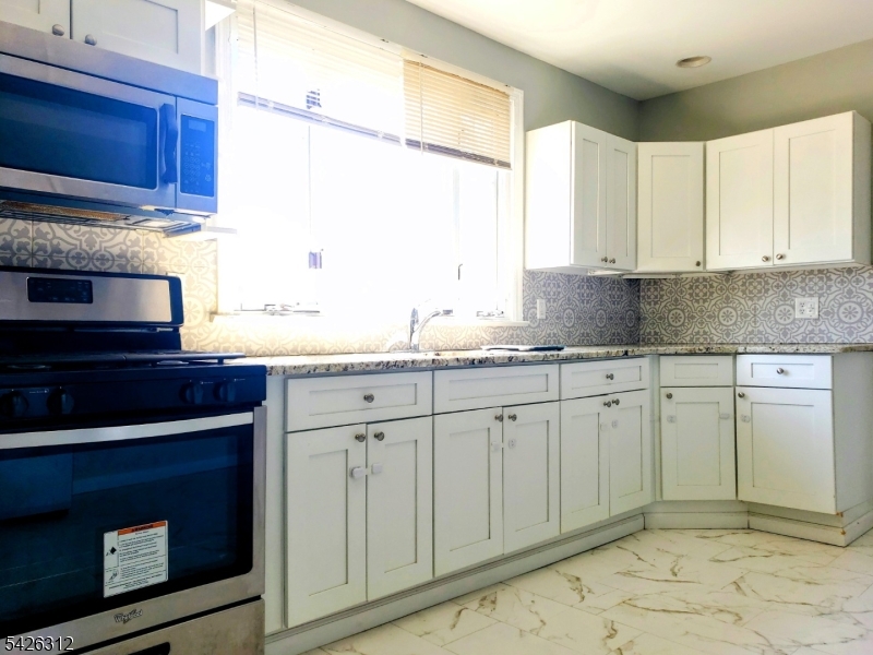 215 Lafayette Street Orange, NJ 07050 - Photo 12 of 14 a kitchen with granite countertop cabinets stainless steel appliances and a sink
