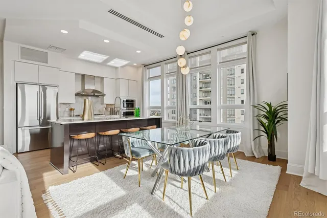 a living room with furniture a dining table and a large window with wooden floor