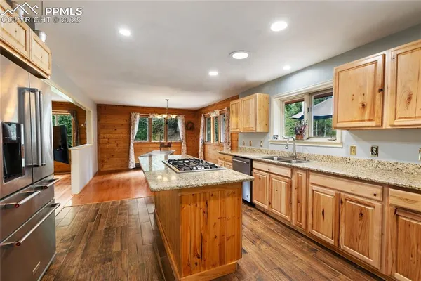 a kitchen with granite countertop a sink stove cabinets and wooden floor