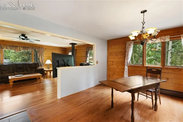 a dining room with wooden floor a chandelier a glass table and chairs