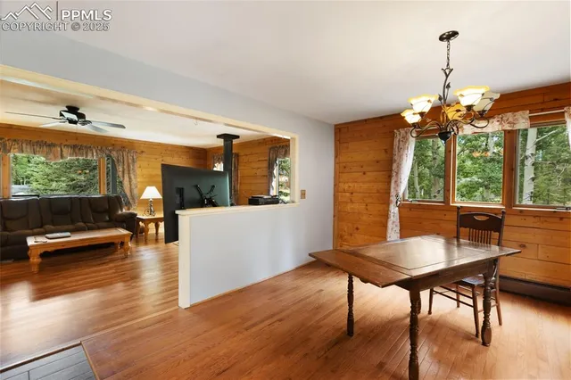 a dining room with wooden floor a chandelier a glass table and chairs