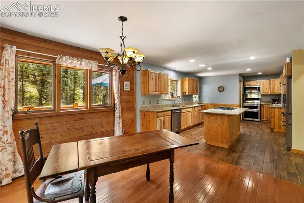 a kitchen with stainless steel appliances wooden floor and large windows