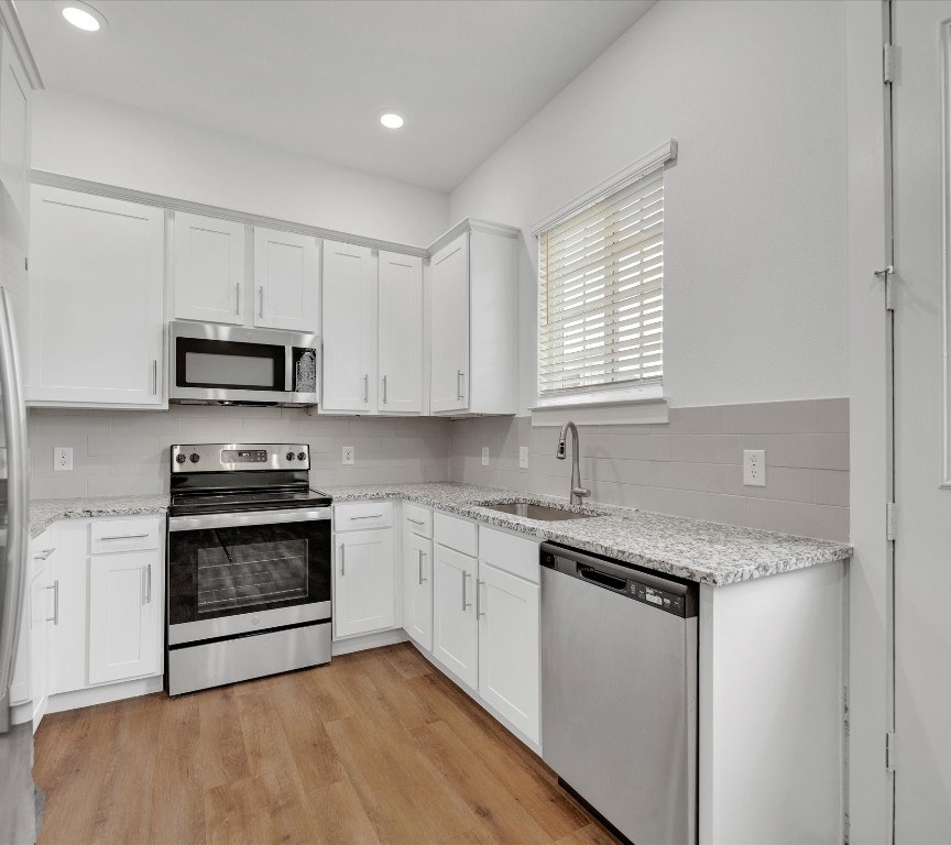 2703-406 Rockhill Road McKinney, TX 75072 - Photo 5 of 14 a kitchen with granite countertop a stove top oven a sink and dishwasher a microwave oven with white cabinets