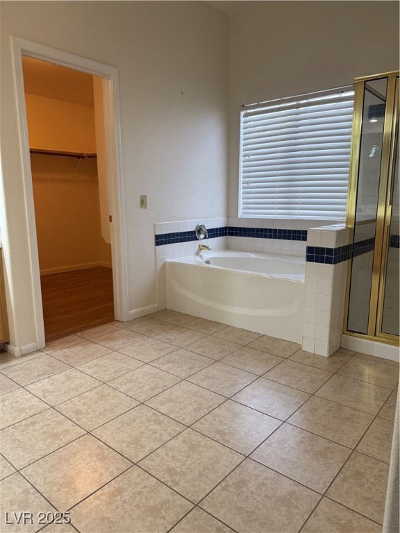 2733 Chokecherry Avenue Henderson, NV 89074 - Photo 18 of 26 Bathroom featuring a walk in closet, a bath, light tile patterned flooring, and a stall shower