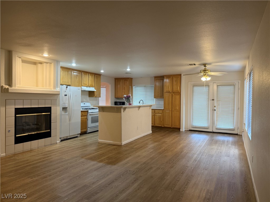 2733 Chokecherry Avenue Henderson, NV 89074 - Photo 3 of 26 Kitchen featuring white appliances, dark wood-style flooring, light countertops, a tiled fireplace, and a kitchen island