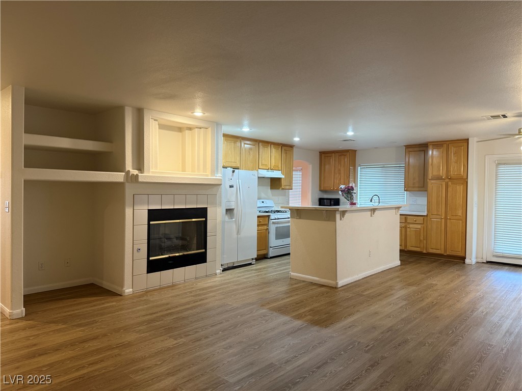 2733 Chokecherry Avenue Henderson, NV 89074 - Photo 4 of 26 Kitchen featuring light wood-style floors, white appliances, a tiled fireplace, light countertops, and recessed lighting