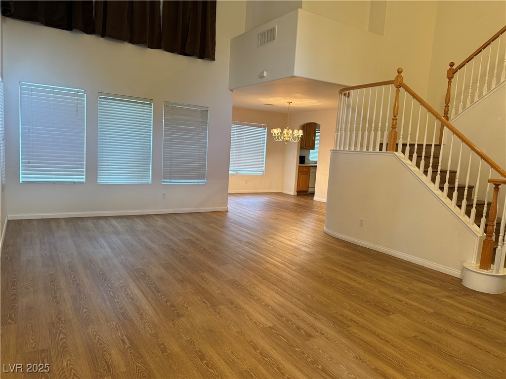 2733 Chokecherry Avenue Henderson, NV 89074 - Photo 9 of 26 Unfurnished living room featuring a chandelier, light wood-style flooring, stairway, and a towering ceiling