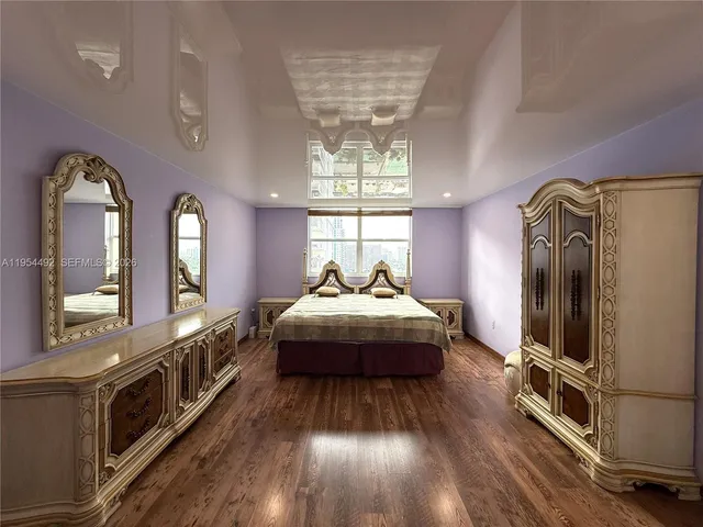 a spacious bedroom with a bed a mirror on dresser and a large window