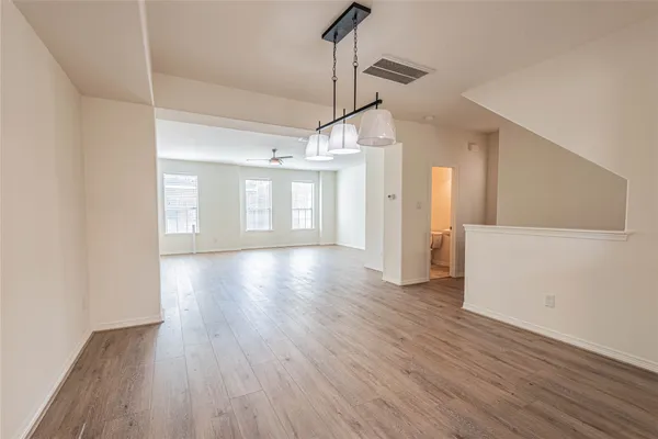 a view of a room with wooden floors and ceiling fan