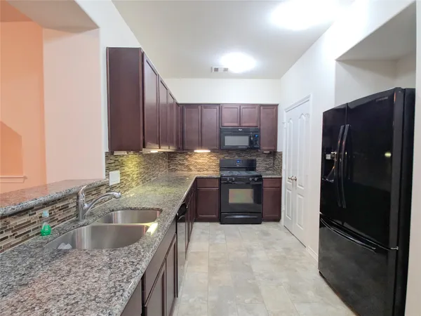 a kitchen with stainless steel appliances granite countertop a refrigerator stove and sink