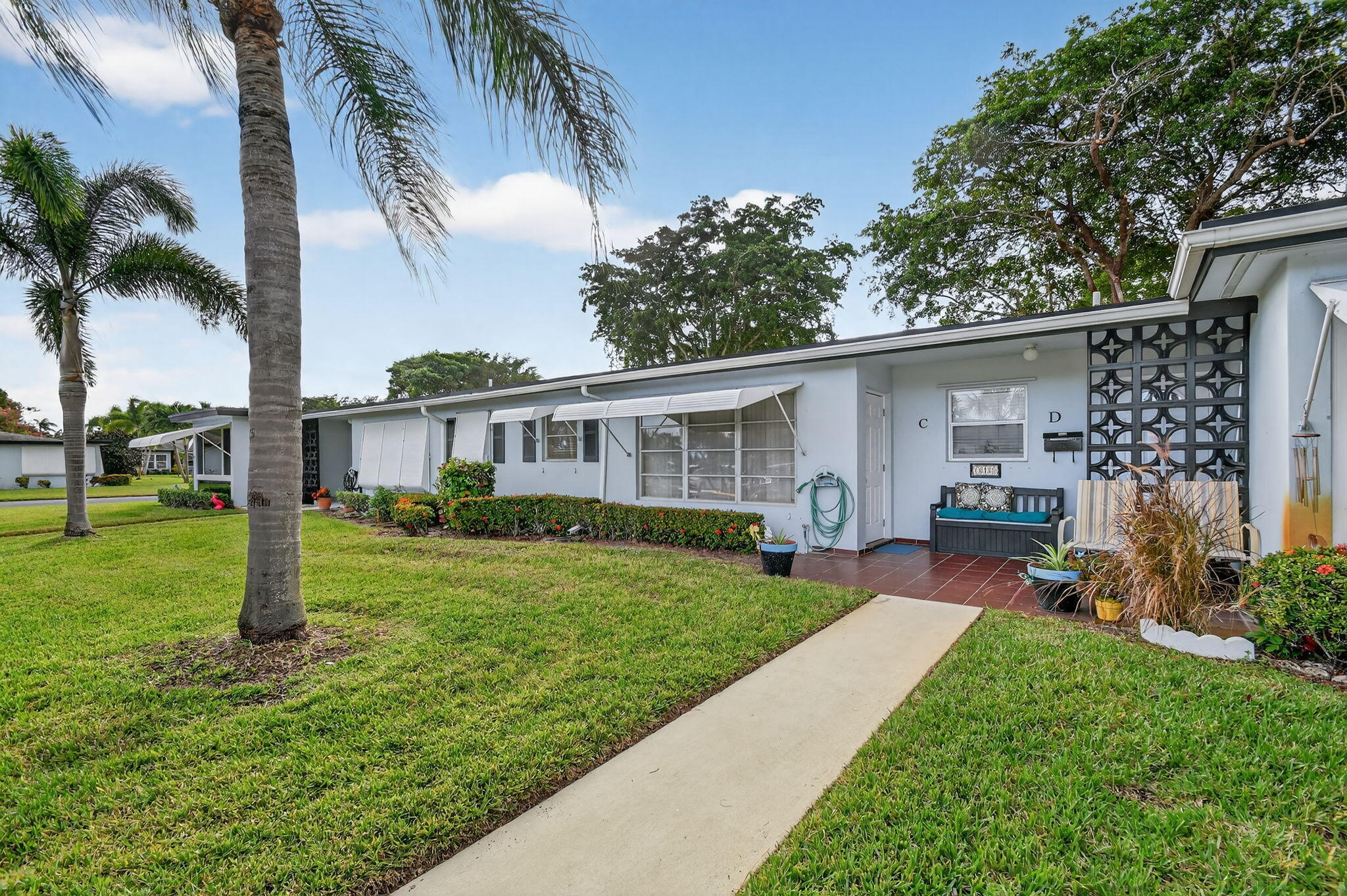 615 High Point Drive, Unit C Delray Beach, FL 33445 - Photo 3 of 48 a front view of a house with a yard and porch
