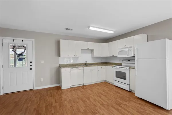 a kitchen with granite countertop white cabinets and white appliances