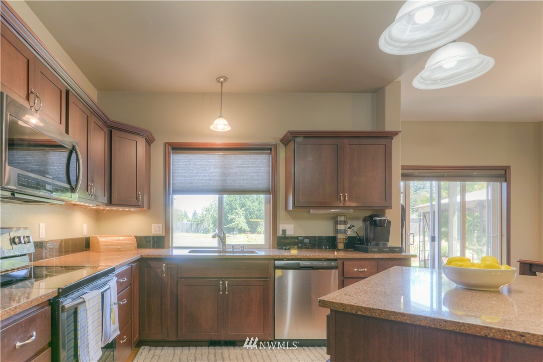 8422 180th Way Southwest Rochester, WA 98579 - Photo 12 of 34 a kitchen with stainless steel appliances granite countertop a sink a stove and a wooden cabinets