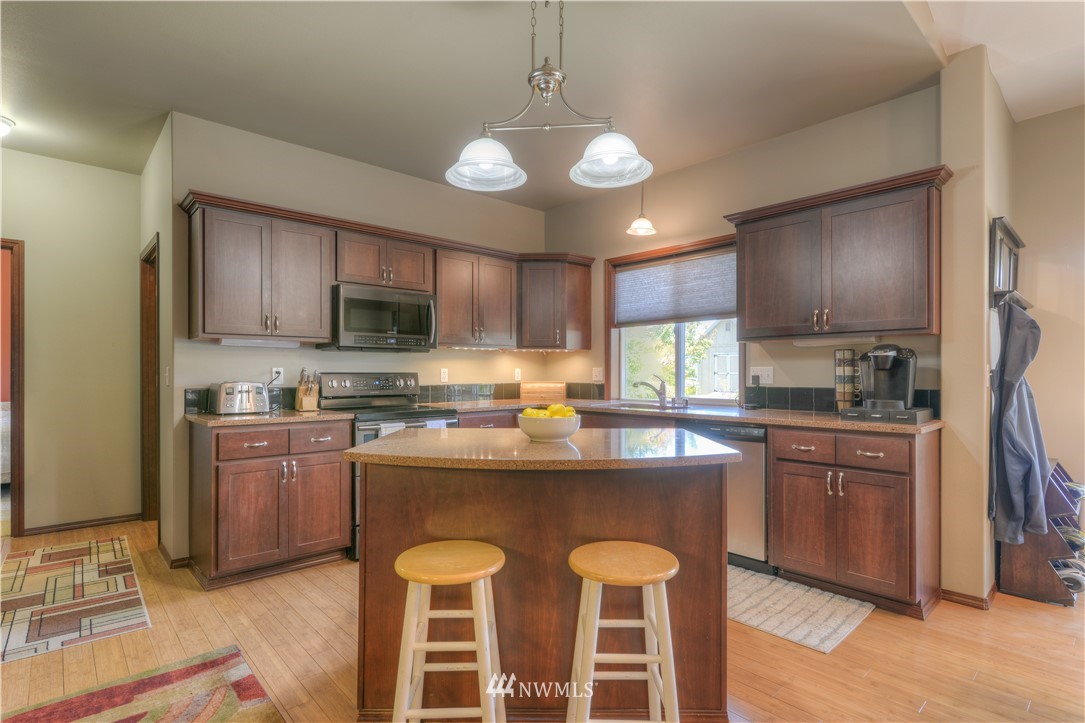 8422 180th Way Southwest Rochester, WA 98579 - Photo 10 of 34 a kitchen with stainless steel appliances granite countertop a stove top oven a refrigerator a sink and dishwasher a oven with wooden cabinets