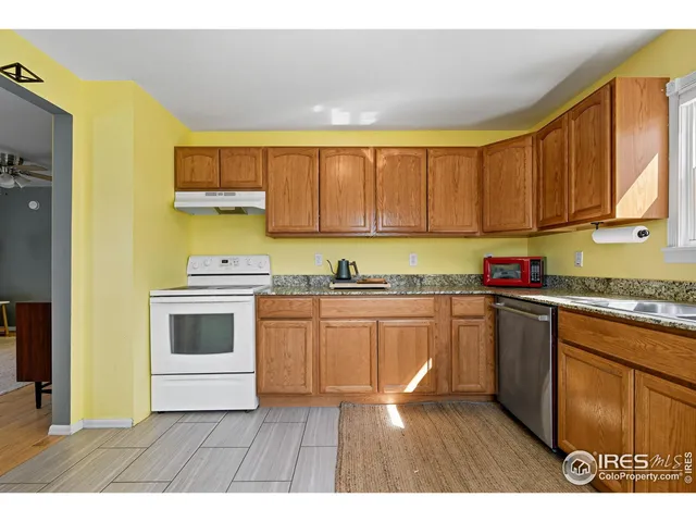 a kitchen with granite countertop a stove a sink dishwasher and a microwave oven with white cabinets