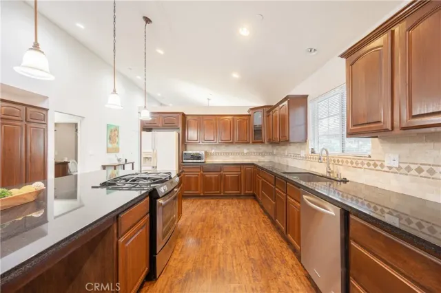 a kitchen with stainless steel appliances granite countertop a sink a stove and a wooden floors
