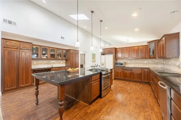 a kitchen with stainless steel appliances granite countertop a sink a stove and a wooden floors