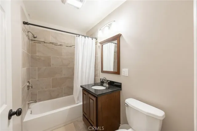 a bathroom with a granite countertop bathtub shower sink mirror and toilet