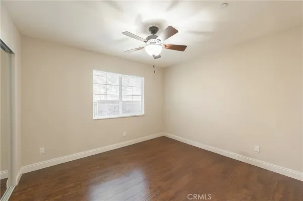 an empty room with wooden floor fan and windows