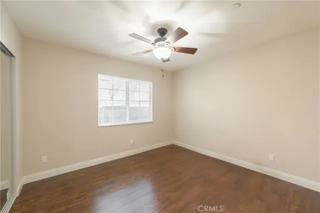 an empty room with wooden floor fan and windows