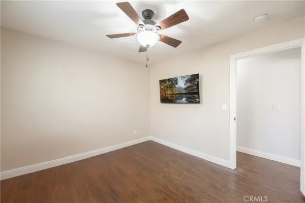 an empty room with wooden floor and ceiling fan