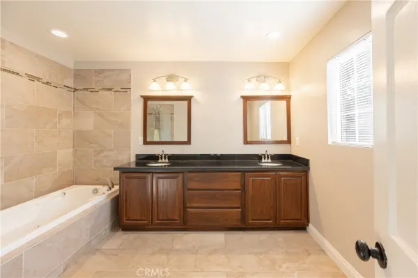 a spacious bathroom with a granite countertop tub double vanity sink and a large mirror