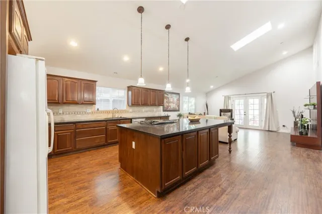 a large kitchen with stainless steel appliances granite countertop a stove a sink dishwasher a refrigerator and wooden floor