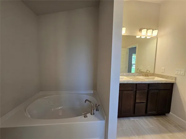 a bathroom with a bathtub sink vanity and mirror