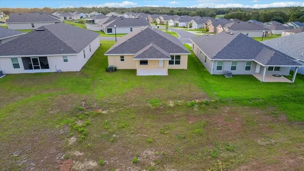 an aerial view of residential houses with outdoor space and trees
