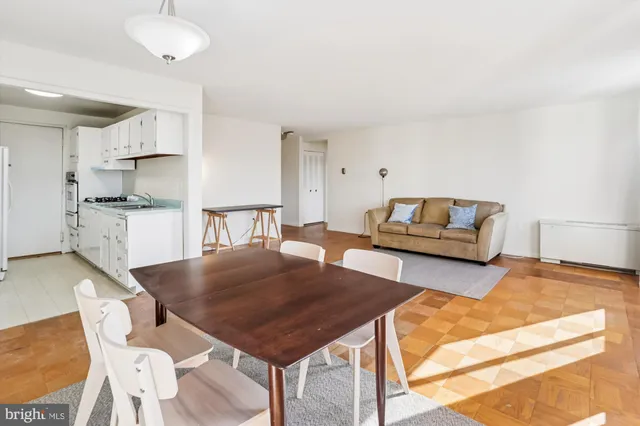 a living room with stainless steel appliances furniture a rug and a kitchen view