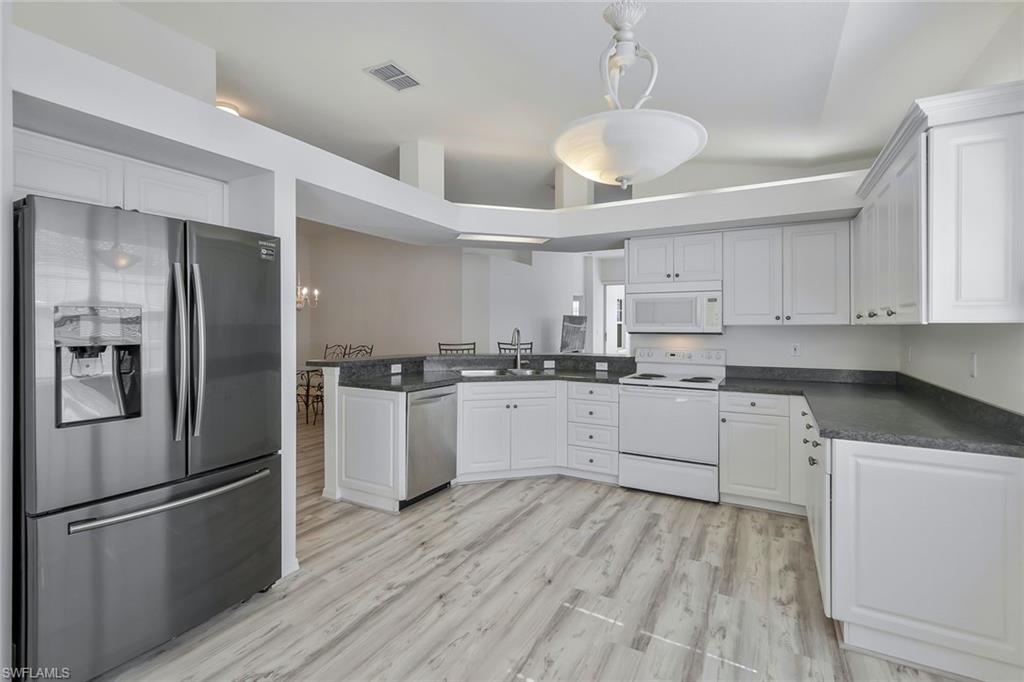 6812 Satinleaf Road South, Unit 204 Naples, FL 34109 - Photo 11 of 39 a kitchen with white cabinets stainless steel appliances and window