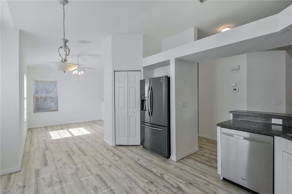 6812 Satinleaf Road South, Unit 204 Naples, FL 34109 - Photo 14 of 39 a kitchen with kitchen island white cabinets and stainless steel appliances