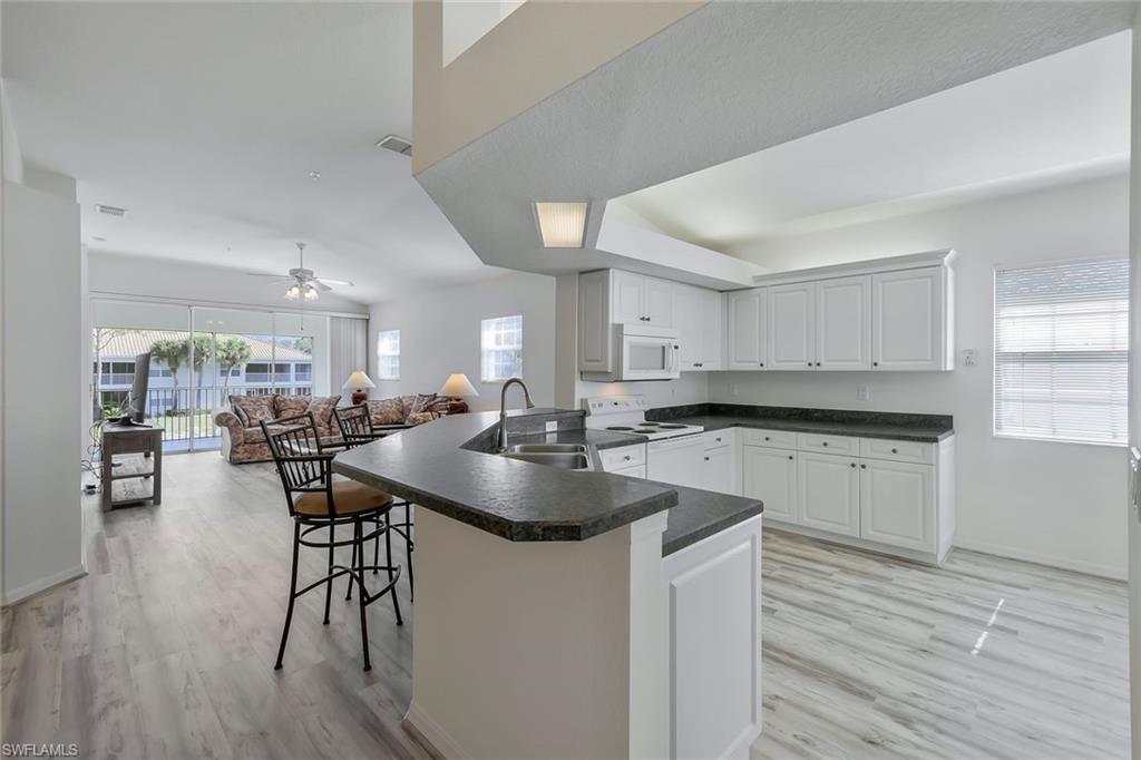 6812 Satinleaf Road South, Unit 204 Naples, FL 34109 - Photo 20 of 39 a kitchen with counter space dining table and chairs