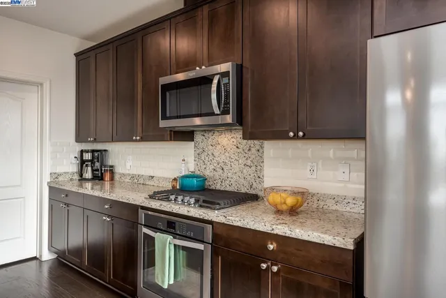 a kitchen with stainless steel appliances granite countertop a stove a microwave a sink and cabinets